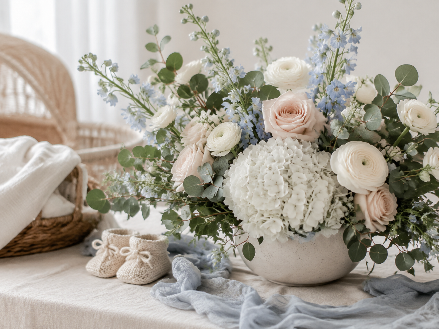Soft blue and white baby shower flowers beside knitted baby booties